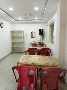 a room with tables and red chairs and a room with shelves at Nasa Hostel in Panchanai
