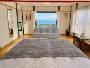 a bedroom with a bed and a couch in front of a window at Natuur one Kamogawa in Minamiboso