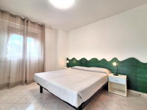 a bedroom with a large bed with a green headboard at Attico Resplendor Fronte mare in Rosolina Mare