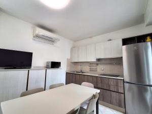 a kitchen with a table and a refrigerator at Attico Resplendor Fronte mare in Rosolina Mare