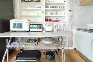 a kitchen with a shelf with a microwave and appliances at Natuur one Kamogawa in Minamiboso +7 photos