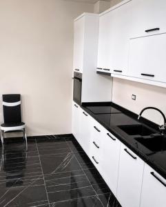 a white kitchen with a sink and a chair at Shengjin City Apartment 1 in Skataj