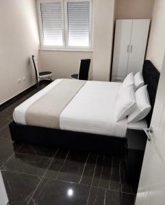 a bedroom with a large bed with two chairs at Shengjin City Apartment 1 in Skataj