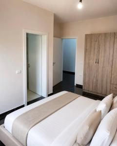 a bedroom with a large white bed and a wooden cabinet at Shengjin City Apartment 1 in Skataj