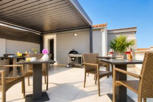 an outdoor patio with tables and chairs and a grill at Casa del Sole - Ugljan Island in Poljana