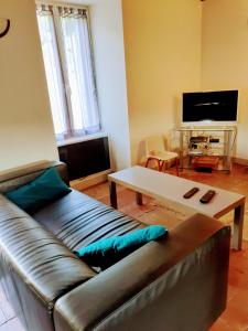 a living room with a leather couch and a coffee table at Gite des Celliers in Alise-Sainte-Reine