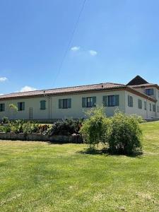a large building with a grass field in front of it at Le Manoir Monlezun in Monlezun