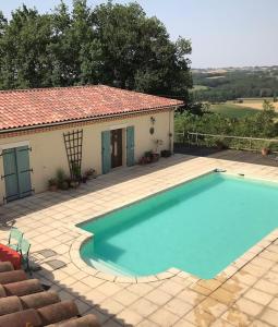 a large blue swimming pool in front of a house at Le Manoir Monlezun in Monlezun +6 photos