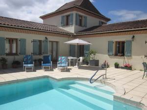 a house with a swimming pool with chairs and an umbrella at Le Manoir Monlezun in Monlezun