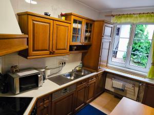 a kitchen with wooden cabinets and a sink and a microwave at Altstadthaus Marille mit Innenhofterrasse in Melk
