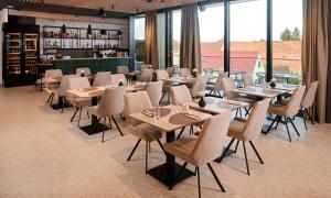 a dining room with tables and chairs and windows at Aminess Florian & Godler Hotel in Karlovac