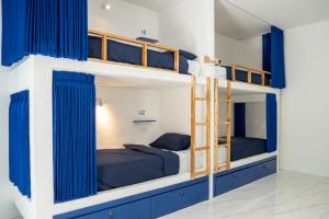 two bunk beds in a room with blue curtains at El Mojo Hostel in Selong Belanak +20 photos