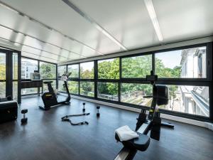 a gym with treadmills and ellipticals in a room with windows at Mercure Paris Ouest Saint Germain in Saint-Germain-en-Laye