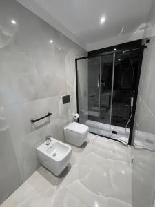 a white bathroom with a toilet and a shower at Gheloi Room in Gela +23 photos