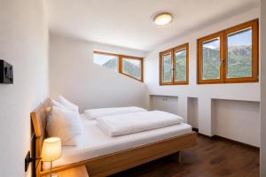 a bedroom with a bed with white sheets and windows at Ferienwohnungen Preiss - Schenna in Schenna