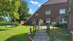 a house with a wooden walkway next to a building at Ferienhof Harlenest in Wittmund