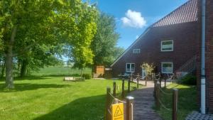 a brick building with a walkway next to a yard at Ferienhof Harlenest in Wittmund