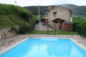 a large blue swimming pool in front of a house at El Cuelebre in Arancedo +4 photos