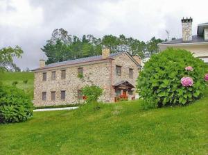 a large stone house on a grassy hill at El Cuelebre in Arancedo