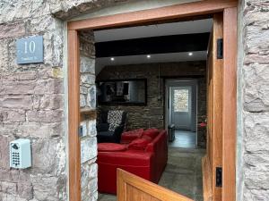 a living room with a red couch in a stone wall at 10 Crickhowell Cottages, Standard Street, Central Crickhowell in Crickhowell +48 photos