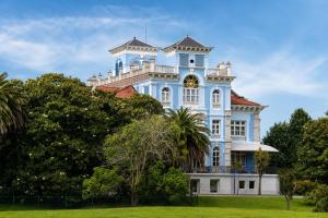 a blue and white building with trees in front of it at Apartamento La Castañera in Colombres