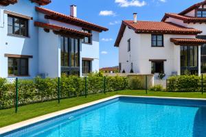 a villa with a swimming pool in front of a house at Apartamento La Castañera in Colombres