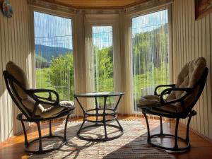 two chairs and a table in a room with windows at Yaremche Potik Guest House in Yaremche +14 photos