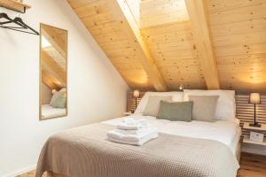 ein Schlafzimmer mit einem weißen Bett und Holzdecke in der Unterkunft Studio Lago in Tüscherz-Alfermée