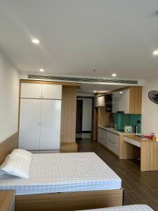 a bedroom with a large bed and a kitchen at L'Azur Cửa Lò in Cửa Lô
