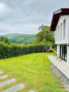 a grassy yard next to a white house with a bench at Villa premium avec extérieur ensoleillé in Urrugne