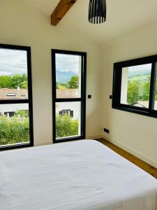 a bedroom with a bed and three windows at Villa premium avec extérieur ensoleillé in Urrugne