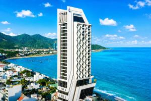 a tall white building next to the ocean at Boton Blue Hotel & Spa in Nha Trang