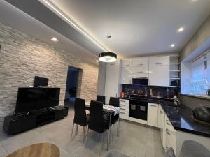 a kitchen with a table and chairs and a tv at Apartament Ala in Zabrze