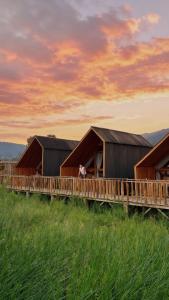 a row of barns with a person sitting on a deck at Dynasty Glamping Bedugul in Bedugul