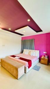 a bedroom with a large bed with pink walls at Palmyra Hotel and Suites in Kollam +4 photos