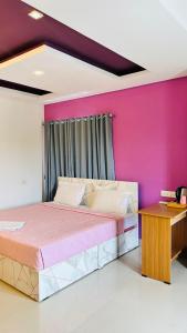 a bedroom with a bed and a pink wall at Palmyra Hotel and Suites in Kollam
