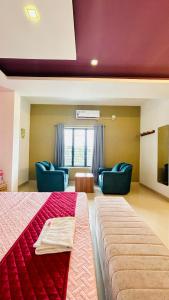 a large room with a bed and two blue chairs at Palmyra Hotel and Suites in Kollam