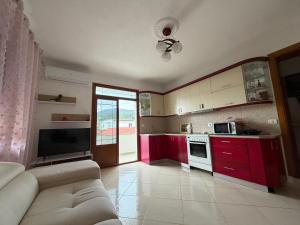 a kitchen with red cabinets and a couch in a room at Cozy Pogradec in Pogradec