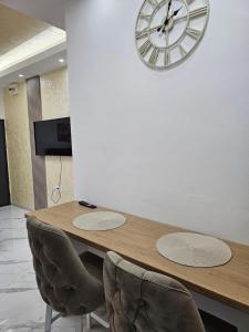 a wooden table with chairs and a clock on a wall at Studio centar Lazic 1 in Šid
