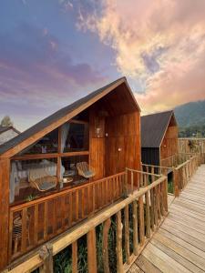 a wooden house with a deck with chairs on it at Dynasty Glamping Bedugul in Bedugul