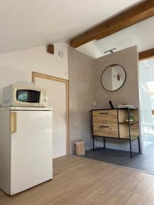 a kitchen with a refrigerator and a table with a microwave at Chez Clémence & Baptiste in Buhl-Lorraine +13 photos