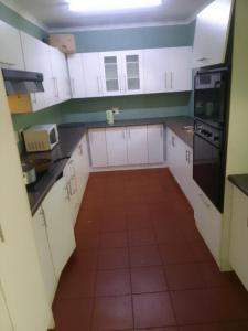 a kitchen with white cabinets and a red tile floor at Star Contractors Accodation with self catering in Mahikeng