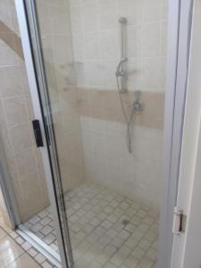 a shower with a glass door with a tiled floor at Star Contractors Accodation with self catering in Mahikeng +15 photos