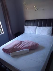 a bed with a pink pillow on top of it at Star Contractors Accodation with self catering in Mahikeng