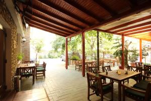 un patio con mesas de madera, sillas y árboles en Hotel Melody, en Oradea