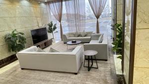 a living room with white couches and a tv at دولف للشقق الفندقية حي المصيف in Hail