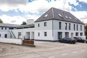 a white house with a car parked in a parking lot at CalmApart Firmenrechnung mit MwSt in Kleinkötz