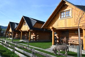 a goat standing in front of a log cabin at Zbojnicky penzion in Jasenica