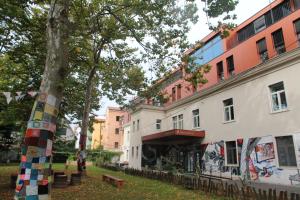 a building with a tree and a building with graffiti at Hostel Pekarna in Maribor