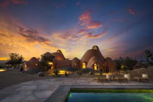 a house with a pool in front of a sunset at Sandora Domes - Architectural Retreat Near National Park in Joshua Tree